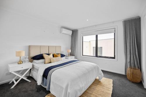 a white bedroom with a large bed and a window at Peninsula Hot Springs Designer Home in Fingal