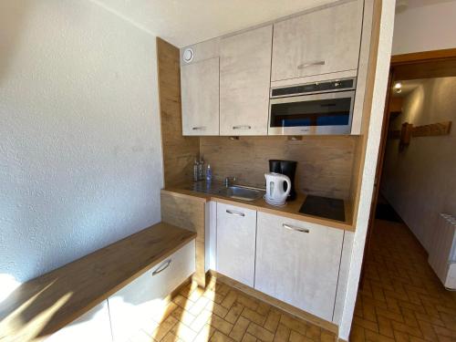 une petite cuisine avec des armoires blanches et un évier dans l'établissement Studio charmant, proche télésiège, parking inclus - FR-1-693-86, à Châtel