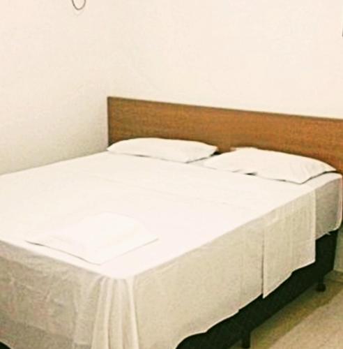 a bed with white sheets and pillows in a room at Royal-inn SPA & Pousada in Itanhaém
