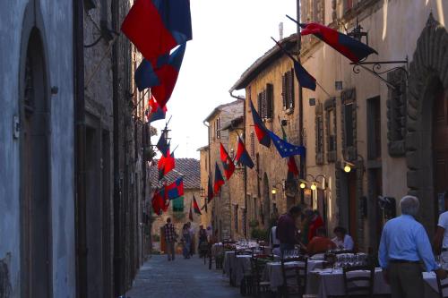 a narrow street with tables and flags on buildings at Le Terrazze Del Chianti b&b Residenza d'Epoca e di Charme in Tavarnelle in Val di Pesa