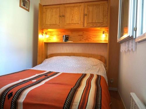 um pequeno quarto com uma cama com armários de madeira em Appartement Bagnères-de-Luchon, 2 pièces, 4 personnes - FR-1-313-127 em Luchon