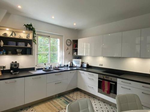 une cuisine avec des armoires blanches et un évier dans l'établissement À 350 m de la plage, superbe T3 rénové avec terrasse et jardin, quartier calme, internet inclus - FR-1-433-92, à Arcachon