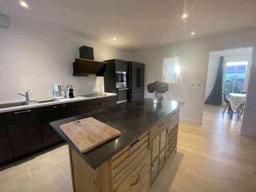 a kitchen with a black counter top and a kitchen island at Grande Maison Rénovée 3* à Bénodet, Jardin Clos, Salle de Jeux, Parking, Wifi, Terrasse, 4 chambres - FR-1-481-112 in Bénodet