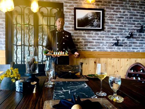 a chef standing in a restaurant with a table with wine glasses at The Capoe House in Haputale