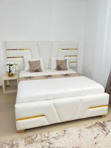 ein weißes Schlafzimmer mit einem großen weißen Bett mit Kissen in der Unterkunft Appartement somptueux à Kotto in Douala