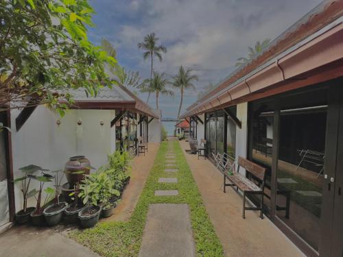 a walkway between two buildings with benches and palm trees at The Shore Samui in Bang Rak Beach