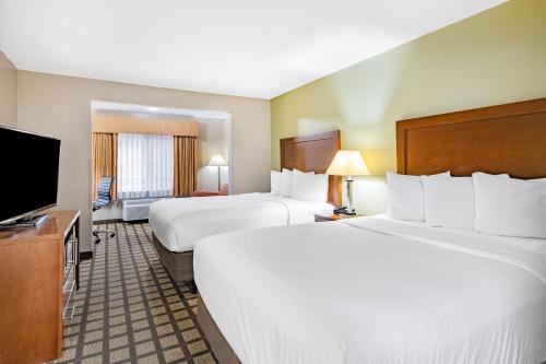 a hotel room with two beds and a flat screen tv at Baymont by Wyndham Gurnee in Gurnee