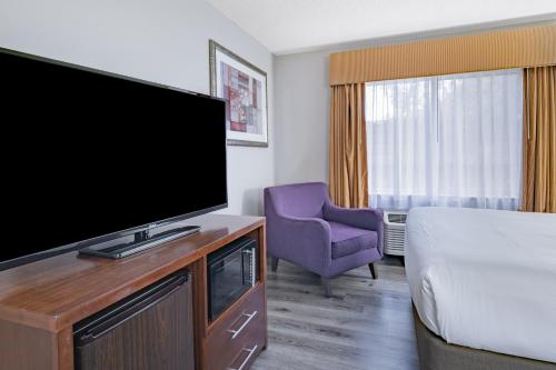 a hotel room with a flat screen tv and a bed at Baymont by Wyndham Gurnee in Gurnee