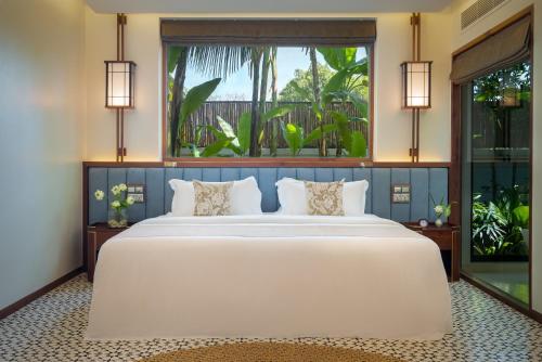 a bedroom with a large white bed and a large window at WAKA VILLA Private Resort & Spa - Adults Only in Siem Reap