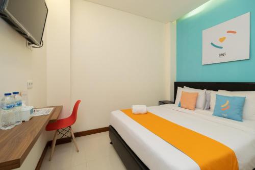 a bedroom with a bed and a desk and a television at Sans Hotel Suryakencana Bogor in Bogor