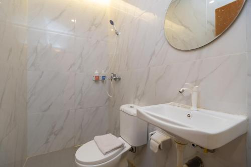 Baño blanco con lavabo y espejo en Sans Hotel Suryakencana Bogor en Bogor