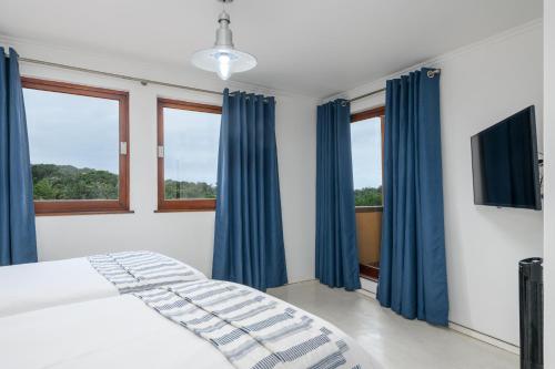 a bedroom with blue curtains and a bed with a television at San Lameer Villa 2818 - 2 Bedroom Classic- 4 pax - San Lameer Rental Agency in Southbroom