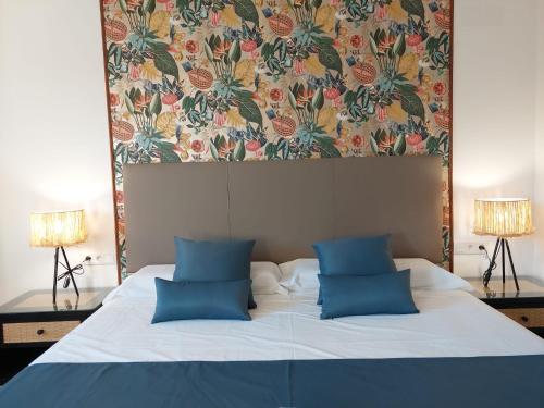 a bed with two blue pillows and a floral headboard at Hostal GARDEN ROUS in Paiporta