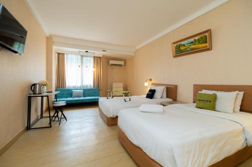 Urbanview Hotel Kebayoran Baru Blok S في جاكرتا: غرفة فندقية بسريرين واريكة