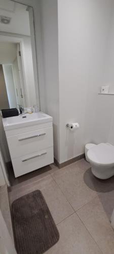 a white bathroom with a toilet and a sink at Pebble Beach 242 in Umhlanga