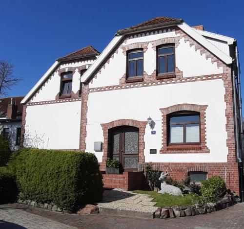 a white house with a red brick at FeWo Kajüte 10 - Carolinensiel in Carolinensiel