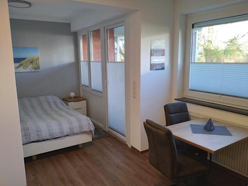 Schlafzimmer mit einem Bett, einem Schreibtisch und einem Tisch in der Unterkunft FeWo Kleine Freiheit mit Balkon - Horumersiel in Horumersiel