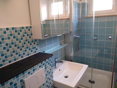 ein blau gefliestes Bad mit einem Waschbecken und einem WC in der Unterkunft FeWo Kleine Freiheit mit Balkon - Horumersiel in Horumersiel