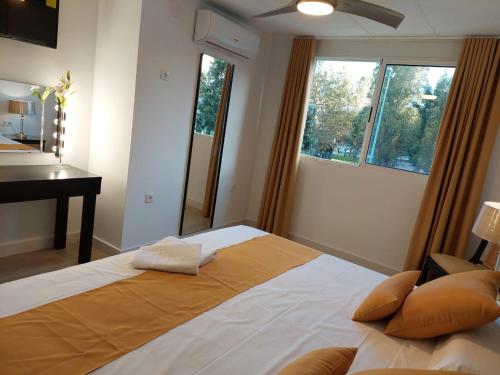 a bedroom with a bed and a desk and two windows at Hostal GARDEN ROUS in Paiporta