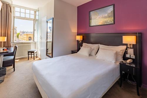a bedroom with a large white bed and a purple wall at Hôtel Le Mondon in Metz