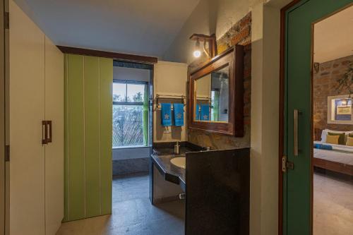a bathroom with a sink and a mirror at SaffronStays Lake House Bouganvillea, Nashik - rustic pool villa with great lake views and patio dining in Nashik