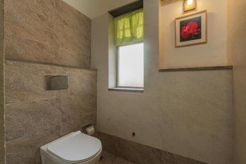 a bathroom with a toilet and a window at SaffronStays Lake House Bouganvillea, Nashik - rustic pool villa with great lake views and patio dining in Nashik
