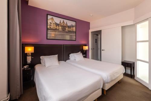 a hotel room with two beds and a purple wall at Hôtel Le Mondon Metz in Metz
