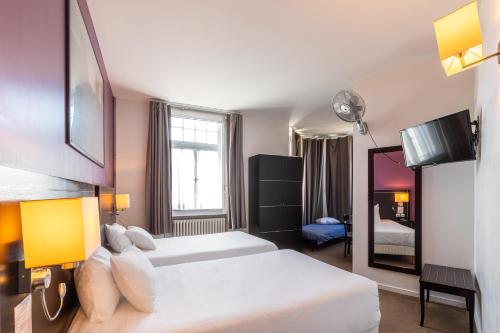 a hotel room with two beds and a mirror at Hôtel Le Mondon Metz in Metz