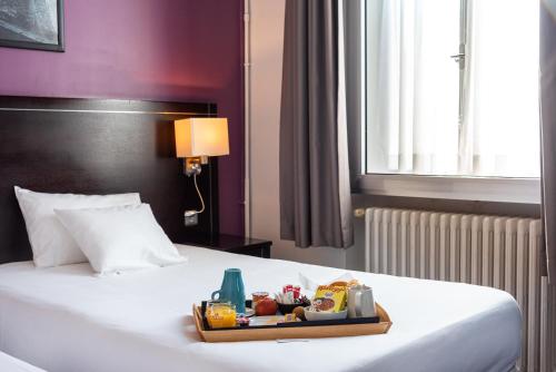 a tray of food on a bed in a hotel room at Hôtel Le Mondon Metz in Metz