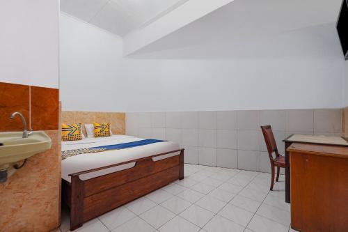 a bedroom with a bed and a sink and a chair at SPOT ON Sartika Inn Pati in Pati