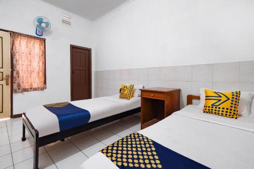 a room with two beds and a dresser in it at SPOT ON Sartika Inn Pati in Pati