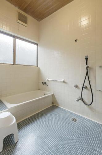 a bathroom with a tub and a toilet and a shower at Jokan-en in Honjo