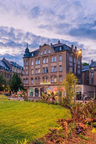 a large building with a lawn in front of it at Hôtel Le Mondon Metz in Metz