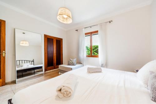 una camera bianca con un grande letto e uno specchio di Playa de Palma Beach House a Playa de Palma