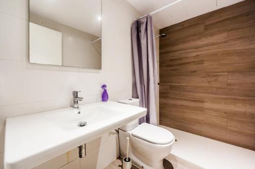 łazienka z toaletą, umywalką i drewnianymi drzwiami w obiekcie Playa de Palma Beach House w mieście Playa de Palma