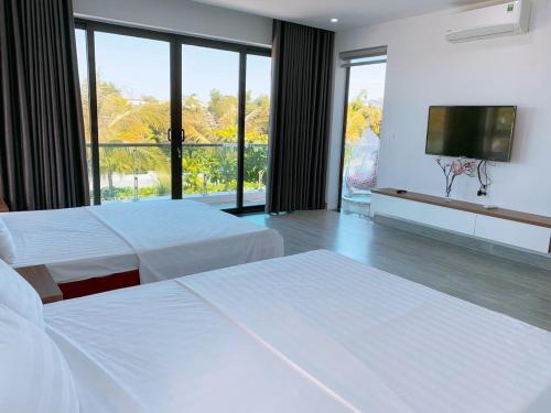 Cette chambre comprend 2 lits et une télévision à écran plat. dans l'établissement Villa FLC Sầm Sơn Vị Trí Trung Tâm View Biển, à Sầm Sơn