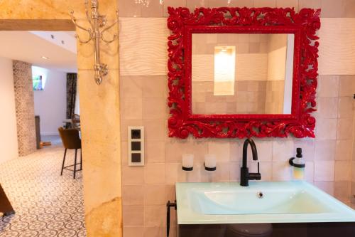 ein Bad mit einem Waschbecken und einem roten Spiegel in der Unterkunft Holzwerk Oybin in Kurort Oybin