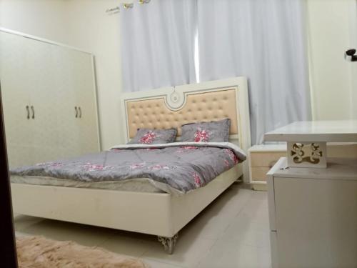 1 dormitorio con cama blanca y almohadas moradas en عجمان, en Ajman