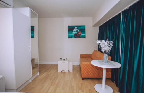a living room with a couch and a table with flowers at Come a Lot Aparthotel Batumi in Batumi