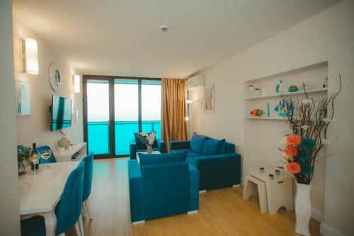 a living room with a blue couch and a table at Come a Lot Aparthotel Batumi in Batumi