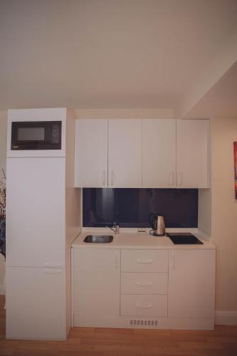 a kitchen with white cabinets and a sink at Come a Lot Aparthotel Batumi in Batumi