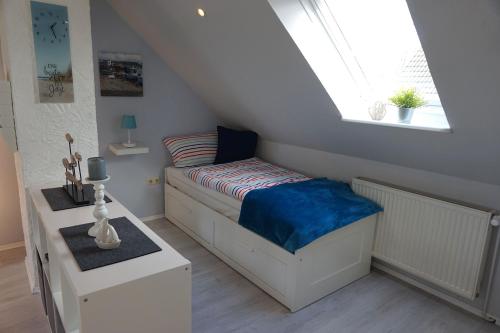 um pequeno quarto com uma cama e uma janela em FeWo Nordseeflair OG - Wiarden em Wiarden