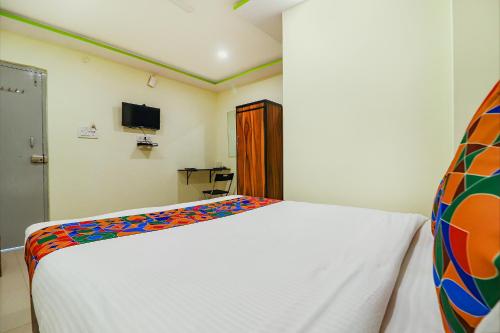 a bedroom with a white bed with a colorful blanket at FabExpress Broholic Suites - Nr JNTU Kukatpally in Hyderabad