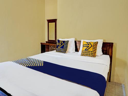 a bedroom with a bed with blue and yellow pillows at OYO 91988 Azka Homestay Klayar in Pacitan