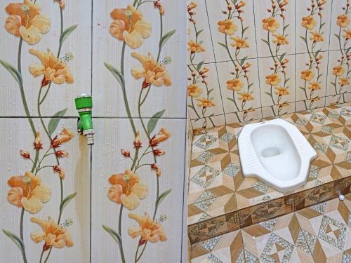 a bathroom with a toilet on a wall with flowers at OYO 91988 Azka Homestay Klayar in Pacitan
