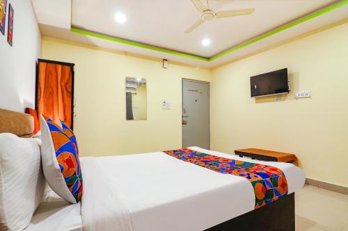 a hotel room with a bed and a tv at FabExpress Broholic Suites - Nr JNTU Kukatpally in Hyderabad