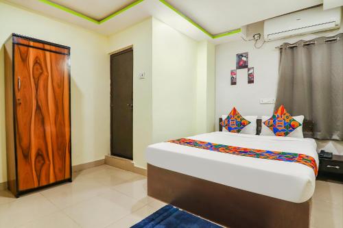 a bedroom with a large bed and a wooden door at FabExpress Broholic Suites - Nr JNTU Kukatpally in Hyderabad