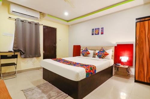 a bedroom with a bed and a desk in it at FabExpress Broholic Suites - Nr JNTU Kukatpally in Hyderabad