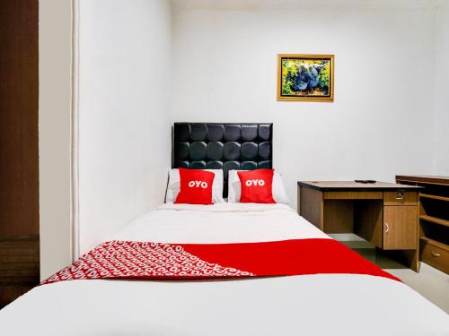 una camera da letto con un grande letto con cuscini rossi di OYO Life 91994 Sawerigading Jatinangor Syariah a Sayang
