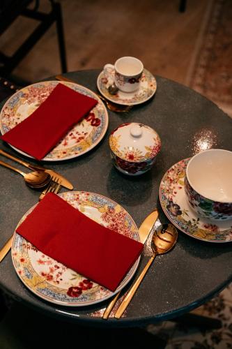 a table topped with plates and cups and spoons at Le Clos Violette et Le 11 D'Aglaé - Hôtel de Charme Design de Luxe in LʼIsle-sur-la-Sorgue